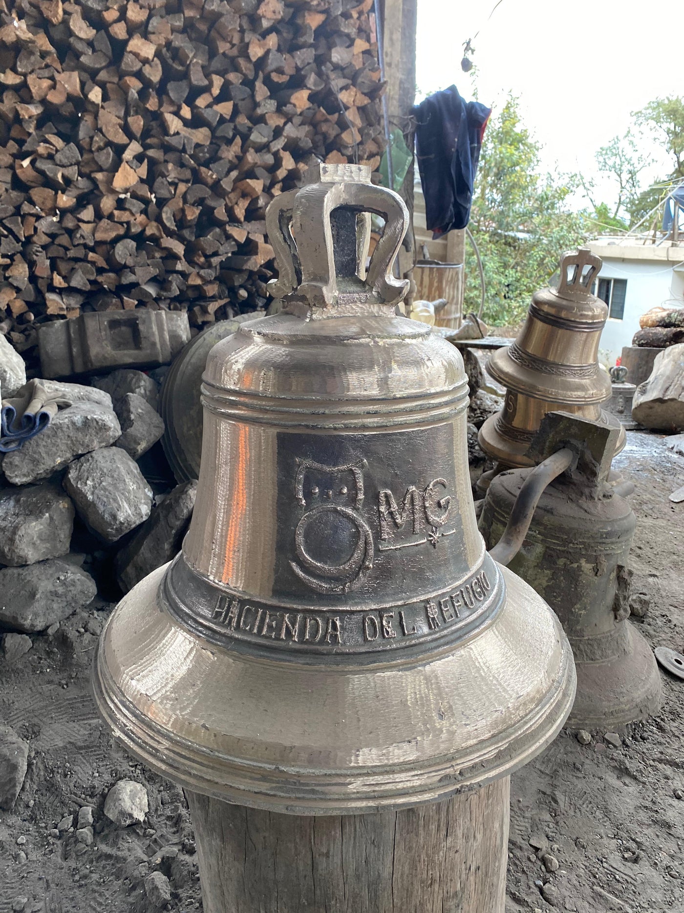 Campana de bronce de Artesanias Jimenez con relieve 'Hacienda del Refugio' en el taller, junto a la lena