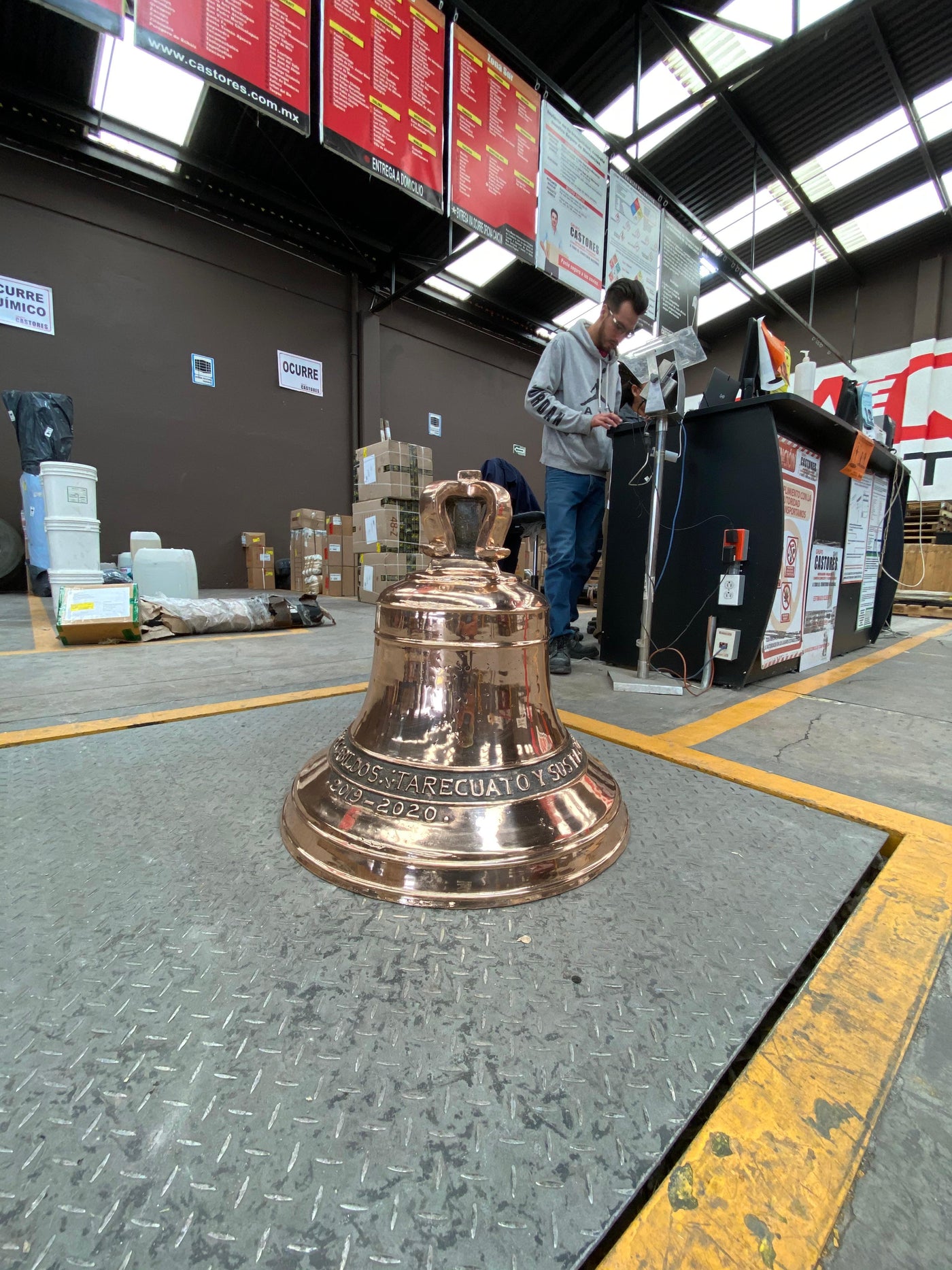 Campana de bronce de Artesanías Jiménez con inscripción 'Tarecuato' lista para envío en la terminal de paquetería